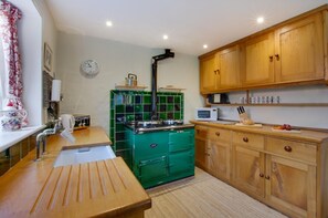 A kitchen with wooden cabinets, a green stove, a microwave, and a sink. - 2 Bed in Letheringsett (oc-endco) (Letheringsett)