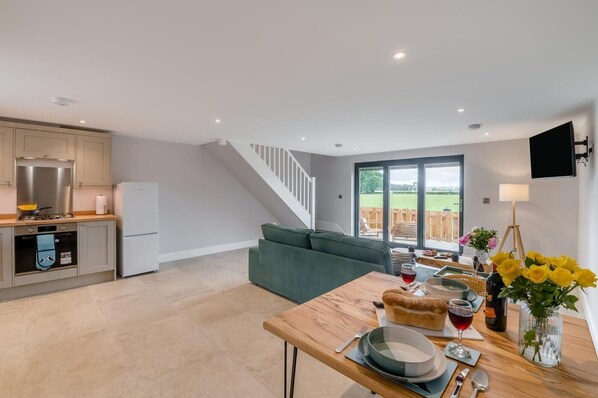 A modern kitchen with a dining area, a staircase, and a view of the outdoors. - 1 Bed in Marishes (oc-l32536) (Marishes)