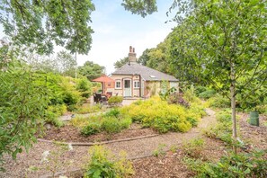 Ein Haus mit Backsteinfassade, einem Schornstein und einer kleinen Terrasse mit Gartenmöbeln.