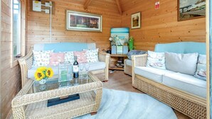 Un intérieur de chalet chaleureux avec un canapé, une table basse en verre et une petite table d’appoint en osier.