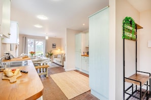 Une cuisine moderne avec un plan de travail en bois, un coin repas avec une table et des chaises, et une vue sur l’extérieur par une fenêtre.