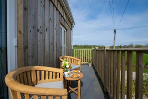Eine Holzterrasse mit Tisch und Stühlen, Blick auf die Landschaft und ein Holzzaun.