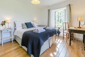 A bedroom with a bed, bedside tables, a desk, and a chair. - 3 Bed in Lostwithiel (oc-cwhite) (Saint Winnow)