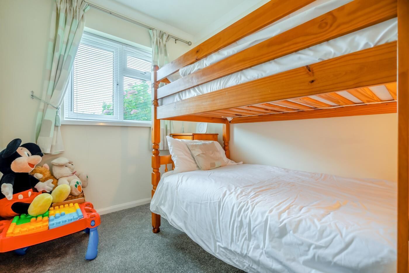 A bunk bed room with a window, a toy car, and plush toys.