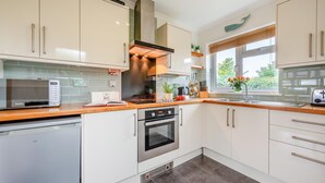 Eine moderne Küche mit weißen Schränken, Edelstahlgeräten und einer Holz Arbeitsplatte.