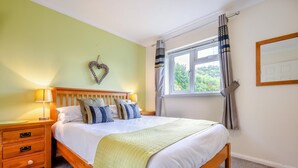 Ein Schlafzimmer mit einem Bett, Nachttischen, einem Fenster mit Vorhängen und einer herzförmigen Dekoration an der Wand.
