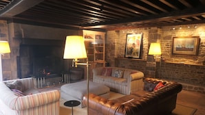 Un salon chaleureux avec une cheminée, des canapés à rayures, un divan en cuir et des murs en pierre.