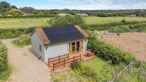 Ett litet hus med ett solpanelbeklätt tak, en träveranda och en grusuppfart.