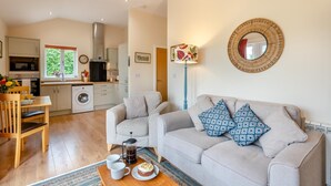 Ett kompakt bostadsutrymme med ett litet kök, en soffgrupp, ett soffbord och en matplats.