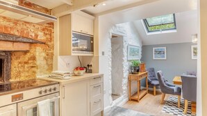Une cuisine moderne avec un mur en briques, un four encastré et un coin repas comprenant une table et des chaises.