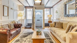 Un salon spacieux avec une cheminée, un canapé en cuir et un grand miroir au mur.