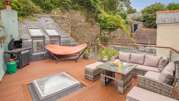 Une terrasse équipée d’un barbecue, d’un hamac et de meubles pour se détendre en plein air.