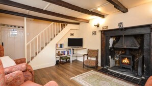 Ein gemütliches Wohnzimmer mit Kamin, Treppe und Fernseher.