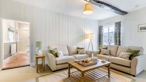 En stue med to sofaer, et sofabord og en lampe. Der er en dør til et badeværelse.