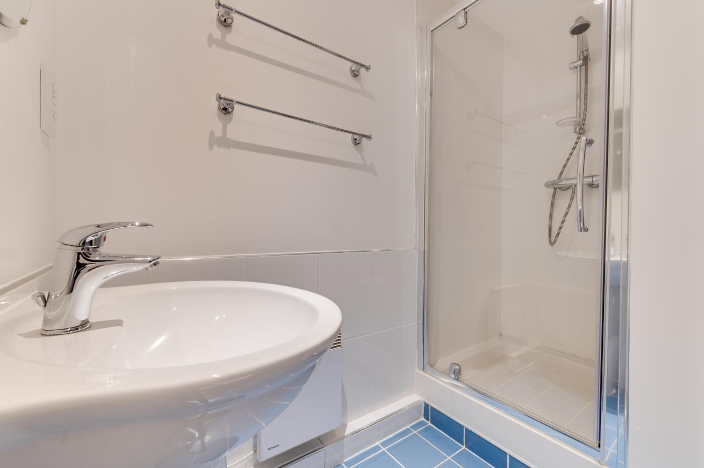 A bathroom with a white sink, chrome faucet, and a glass-enclosed shower.