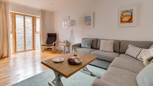 Een moderne woonkamer met een houten salontafel, een grijze bank en een stoel.