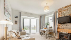 A modern living room with a sofa, a dining table, and a fireplace. - 1 Bed in Tintagel (oc-pc084) (Tintagel)