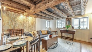 A rustic interior with exposed wooden beams, a patterned wall, a sofa, a coffee table, and a dining area with plates and glasses. - 2 Bed in Battle (oc-f32643) (Battle)