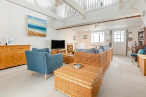 A spacious living room with a television, wicker furniture, and a high ceiling with exposed beams. - 3 Bed in Marazion (oc-p00904) (Marazion)