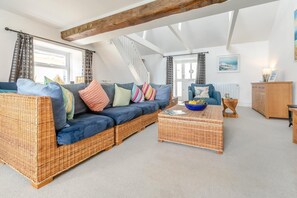 A spacious loft with a large sofa, a coffee table, and a wooden cabinet. - 3 Bed in Marazion (oc-p00904) (Marazion)