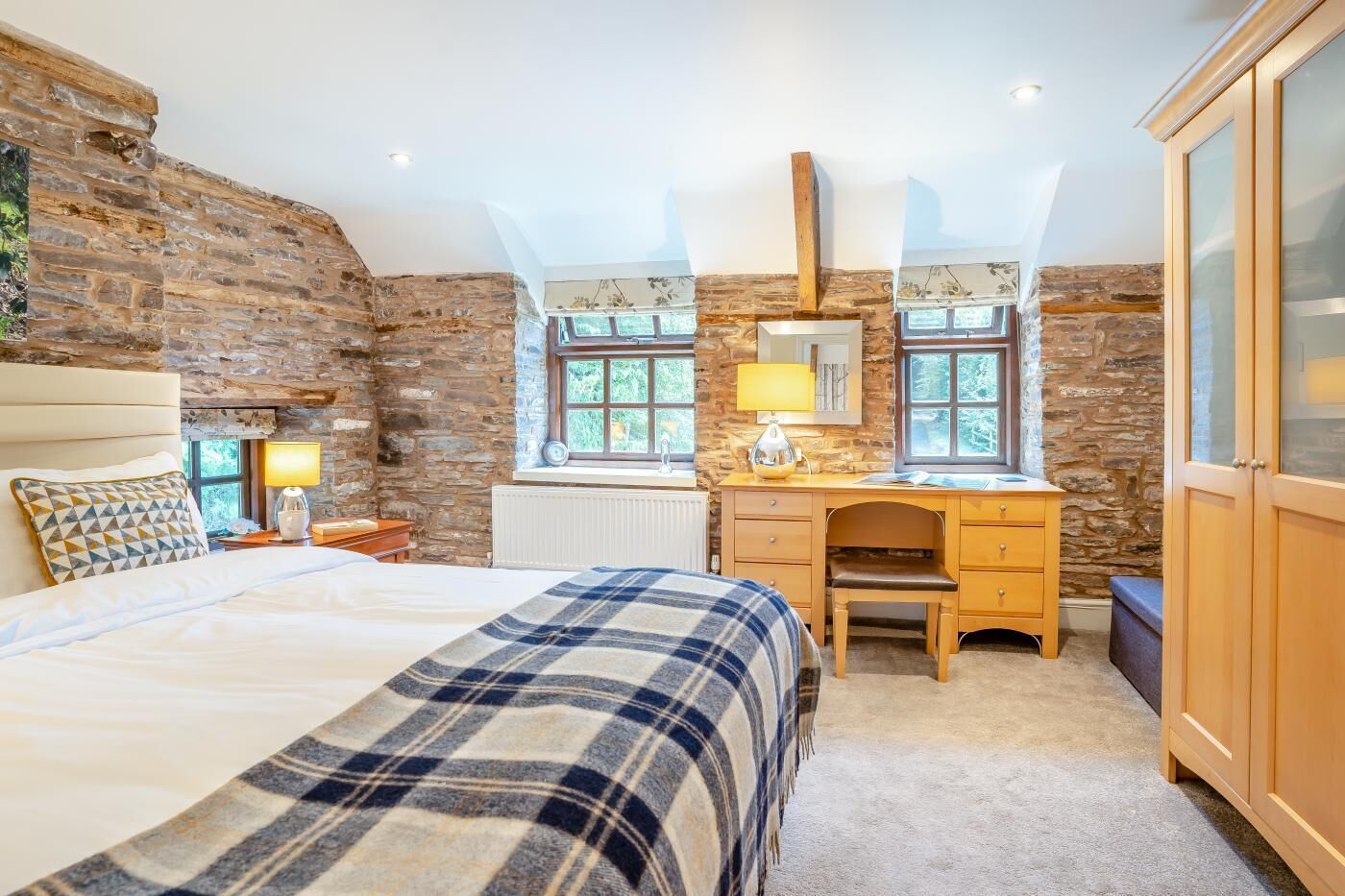 Ein Schlafzimmer mit einem großen Bett, einem Holztisch, einem Stuhl, einem Spiegel und einem Kleiderschrank.