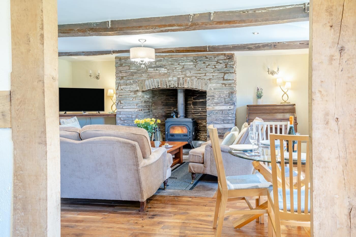 A cozy living room with a stone fireplace, a sofa, a TV, and a dining area with a table and chairs.