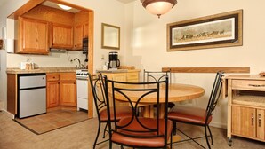 A kitchen with wooden cabinets, a stove, a refrigerator, and a dining table with chairs. - Spacious Studio on Keystone Lake with Full Kitchen (Keystone)