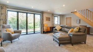 A spacious living room with a grey armchair, a leather sofa, and a wooden staircase. - 2 Bed in Hemblington (oc-2134) (Hemblington)