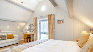 Une chambre à coucher comprenant un lit, un bureau, une chaise, un canapé et une fenêtre avec des rideaux.