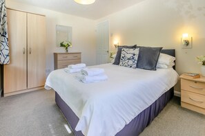 A neatly arranged bedroom with a large bed, a wardrobe, a bedside table with a lamp, and a mirror on the wall. - 2 Bed in Lynton (oc-p13830) (Barbrook)