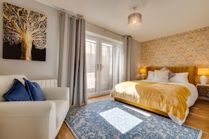 Une chambre à coucher avec un lit, un canapé, un lustre et une grande fenêtre avec des rideaux.
