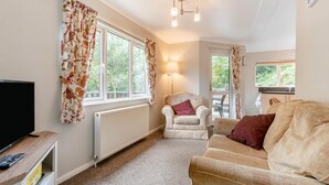 A cozy living room with a television, a comfortable sofa, a chair, and a radiator. - 2 Bed in Lynton (oc-r13823) (Barbrook)