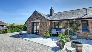 A stone house with a patio, outdoor seating, and a gravel driveway. - 1 Bed in Wadebridge (oc-p00440) (Saint Issey)