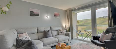 Un salon avec un canapé gris, une table basse en bois et un fauteuil noir.
