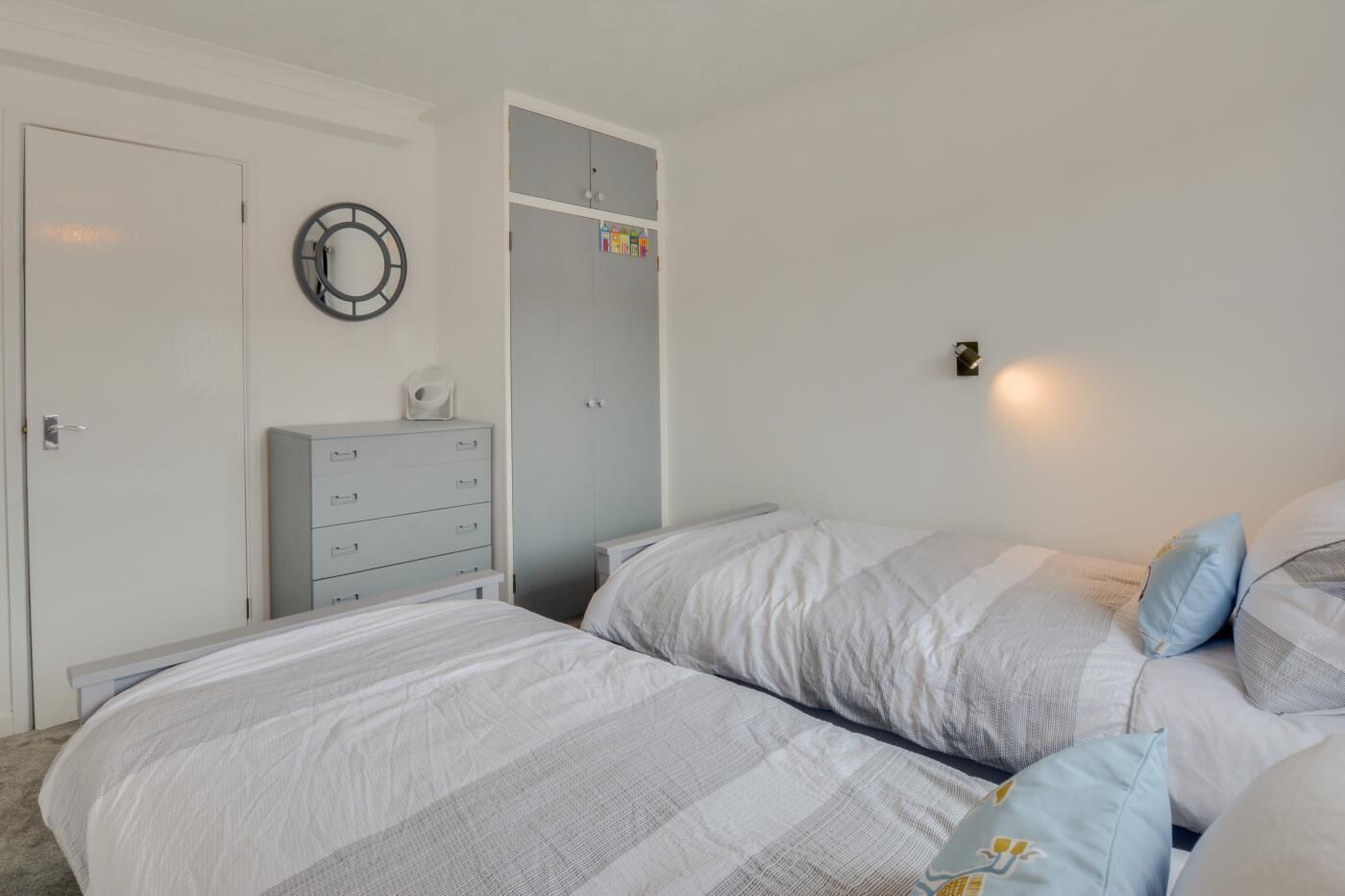 Une chambre à coucher comprenant un lit, une commode, une armoire et une horloge murale.