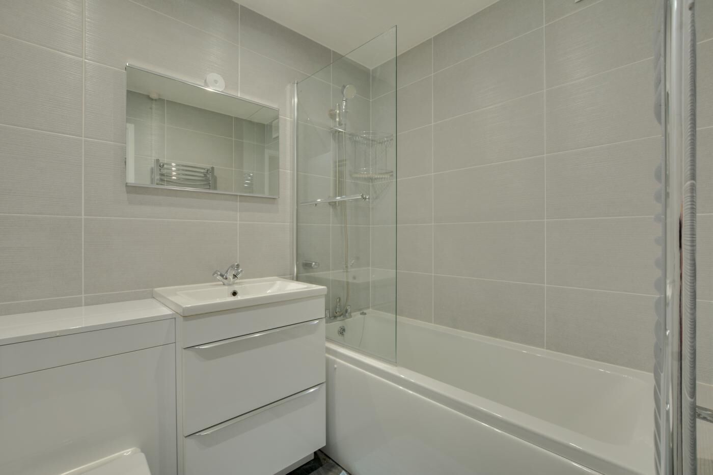 A bathroom with a white sink, mirror, and glass shower enclosure.