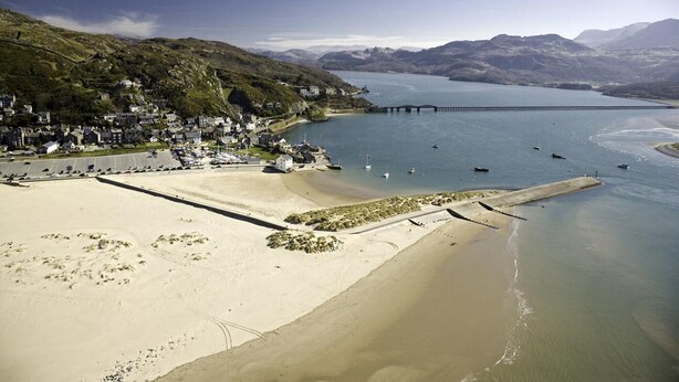 A coastal town with a sandy beach, a pier, and a mountainous backdrop. - 4 Bed in Barmouth (oc-bow259) (Barmouth)