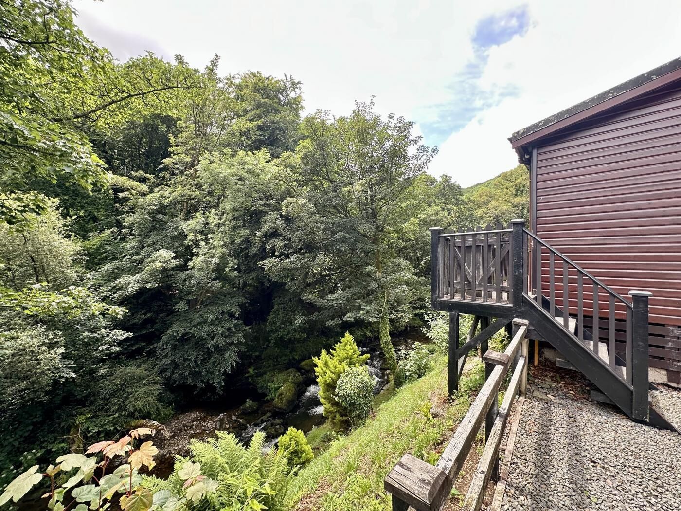 A wooden deck with a metal railing leading to a building with horizontal siding.