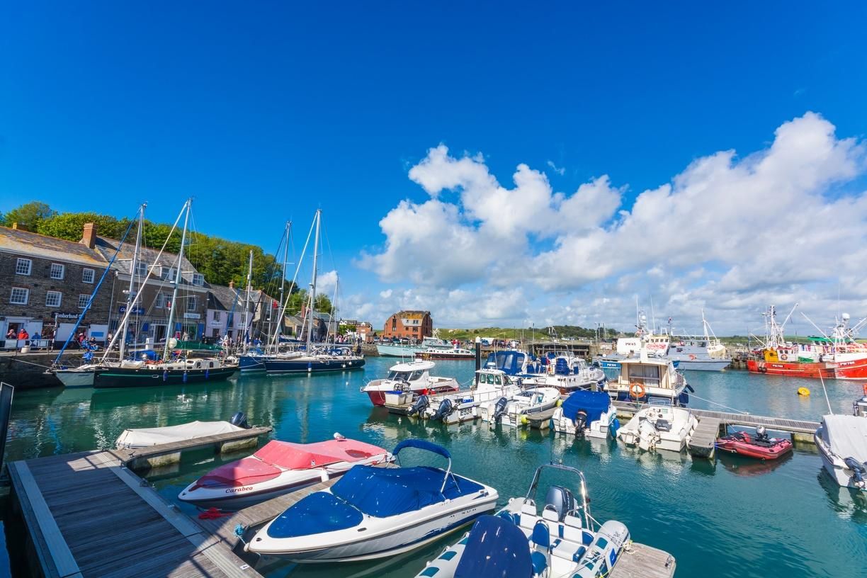 A marina with various boats docked, wooden buildings, and a clear blue sky.