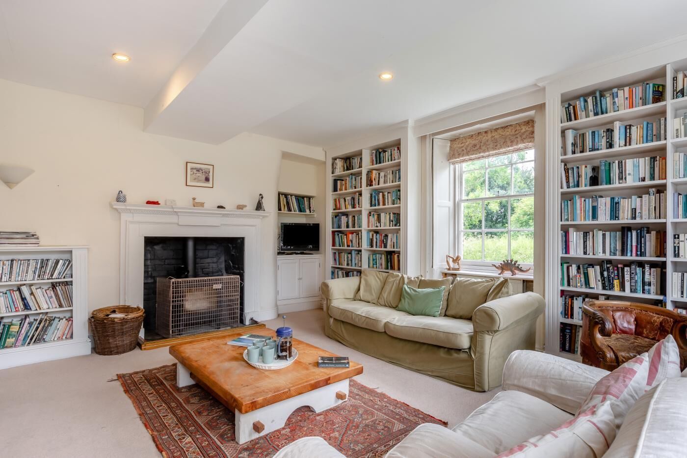 A cozy living room with a fireplace, a sofa, a coffee table, and a bookshelf filled with books.