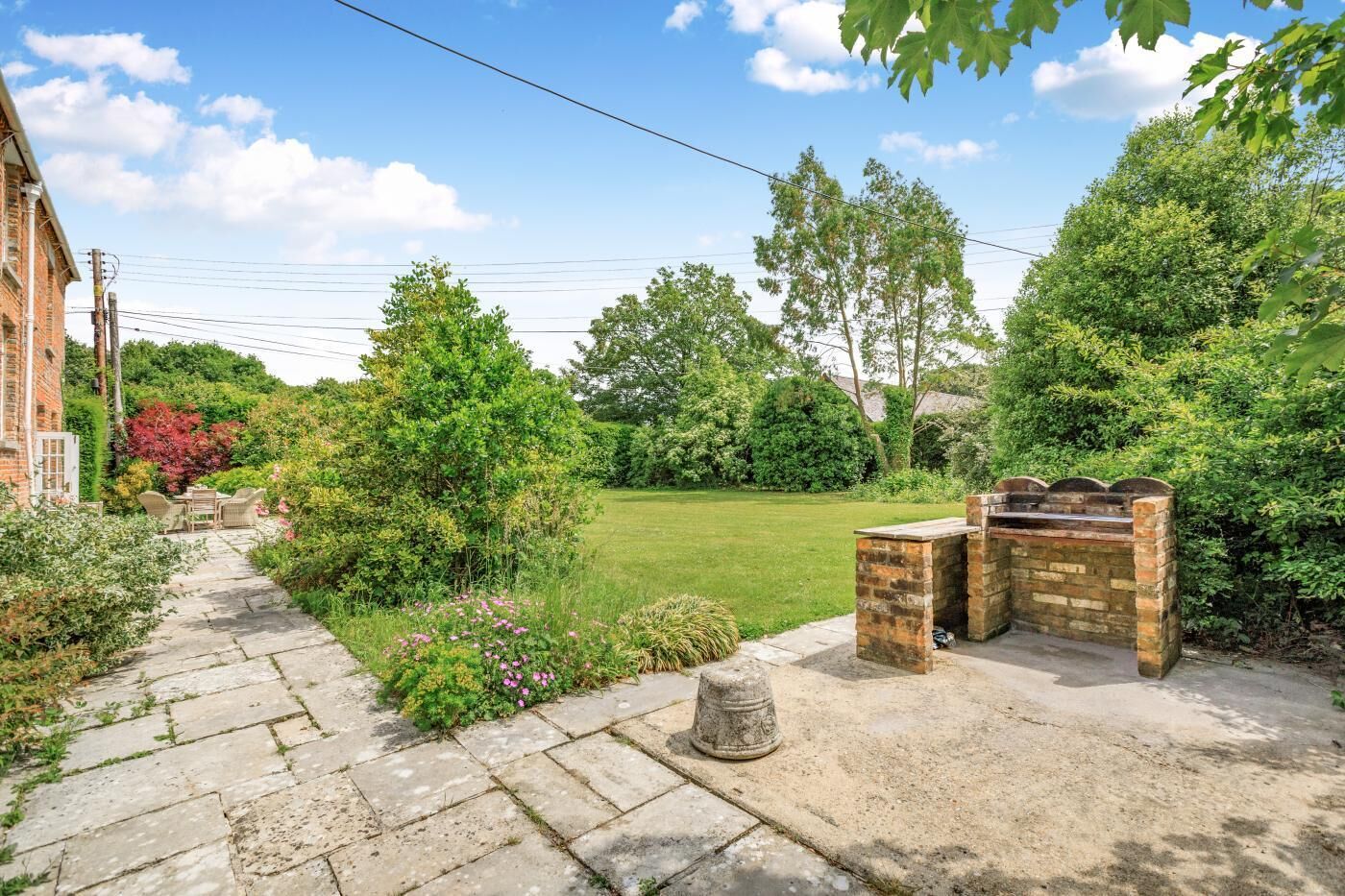 A garden with a stone pathway leading to a brick barbecue area.