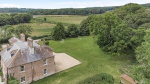 Ein großes Ziegelhaus mit geneigtem Dach, einem gepflegten Rasen und einem kleinen Gartenhaus.
