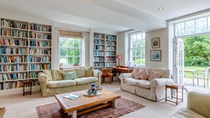 Ein geräumiges Wohnzimmer mit zwei Sofas, einem Couchtisch und einem Bücherregal voller Bücher.