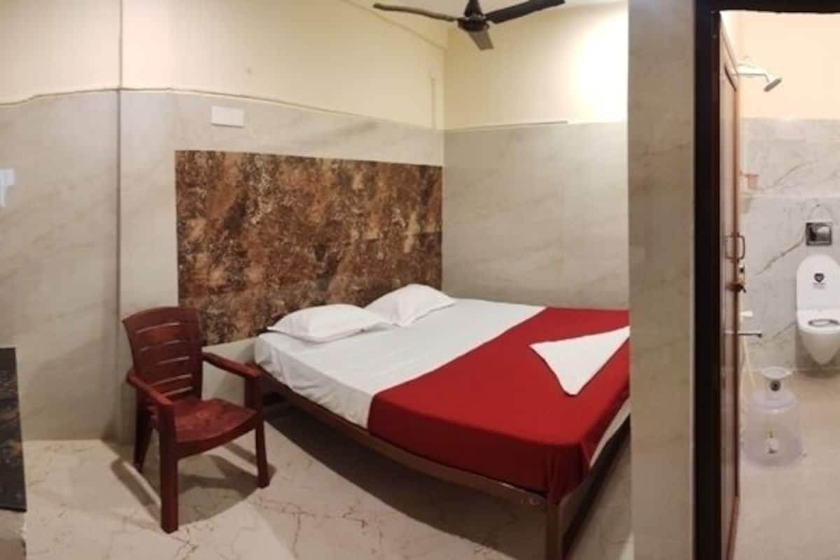 Una habitación de hotel con cama, una silla, televisión y baño completo.
