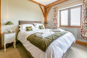 A neatly made bed with pillows, a bedside table with a lamp, and a window with curtains. - 4 Bed in Instow (oc-h32283) (Westleigh)