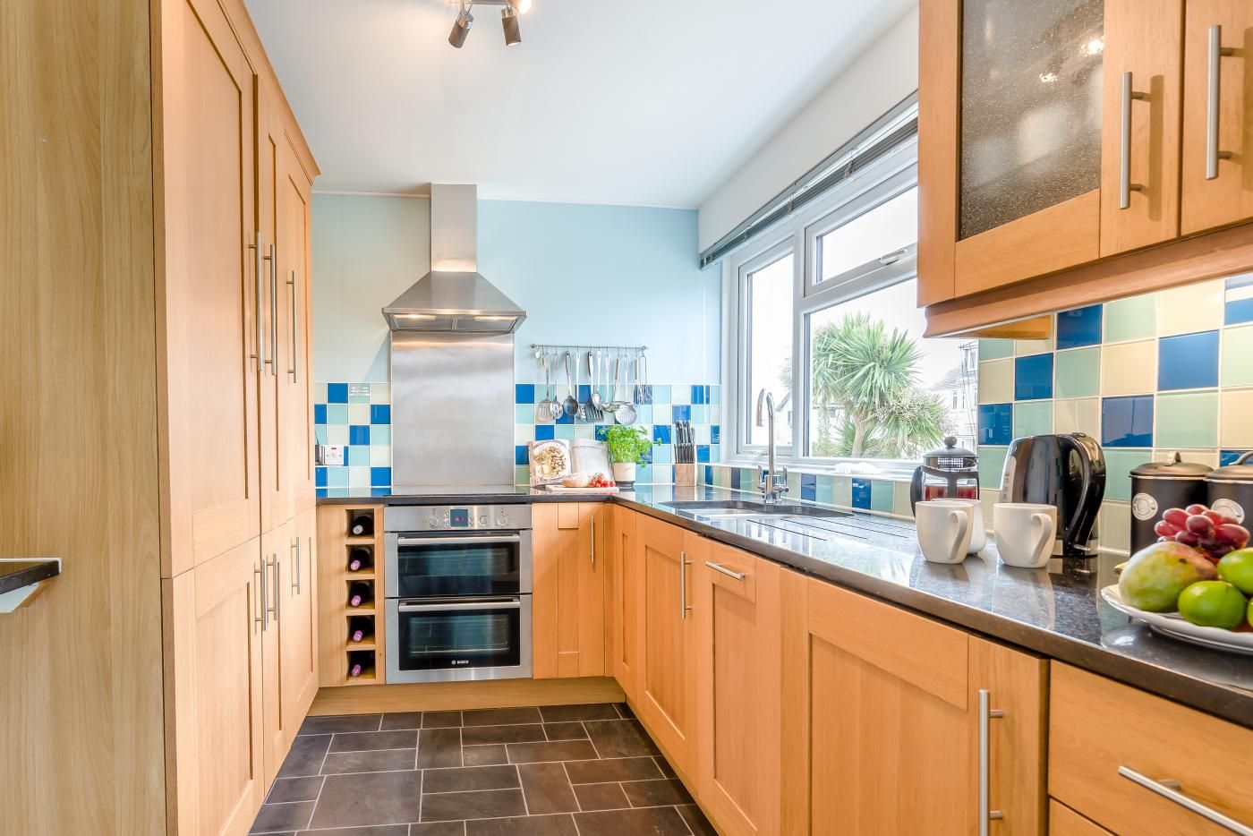 Una cocina moderna con armarios de madera, una campana extractora de acero inoxidable y un ventanal que ofrece luz natural.