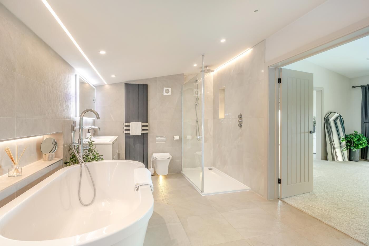 Een moderne badkamer met een vrijstaand bad, een douche met glazen wand en een toilet.