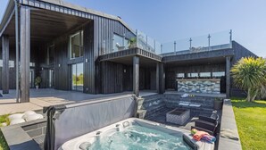 A modern house with a large outdoor hot tub, a covered patio, and a stone fireplace. - 7 Bed in Marwood (oc-w32673) (Marwood)
