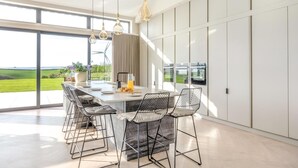 A modern kitchen with a large island, bar stools, pendant lighting, and a view of the outdoors. - 7 Bed in Marwood (oc-w32673) (Marwood)