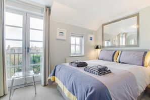 A bedroom with a large bed, a window, a mirror, and a view of the outside. - 2 Bed in Padstow (oc-p00337) (Padstow)